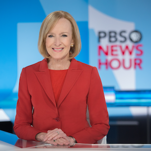 Judy Woodruff sits at the PBS News Hour anchor desk